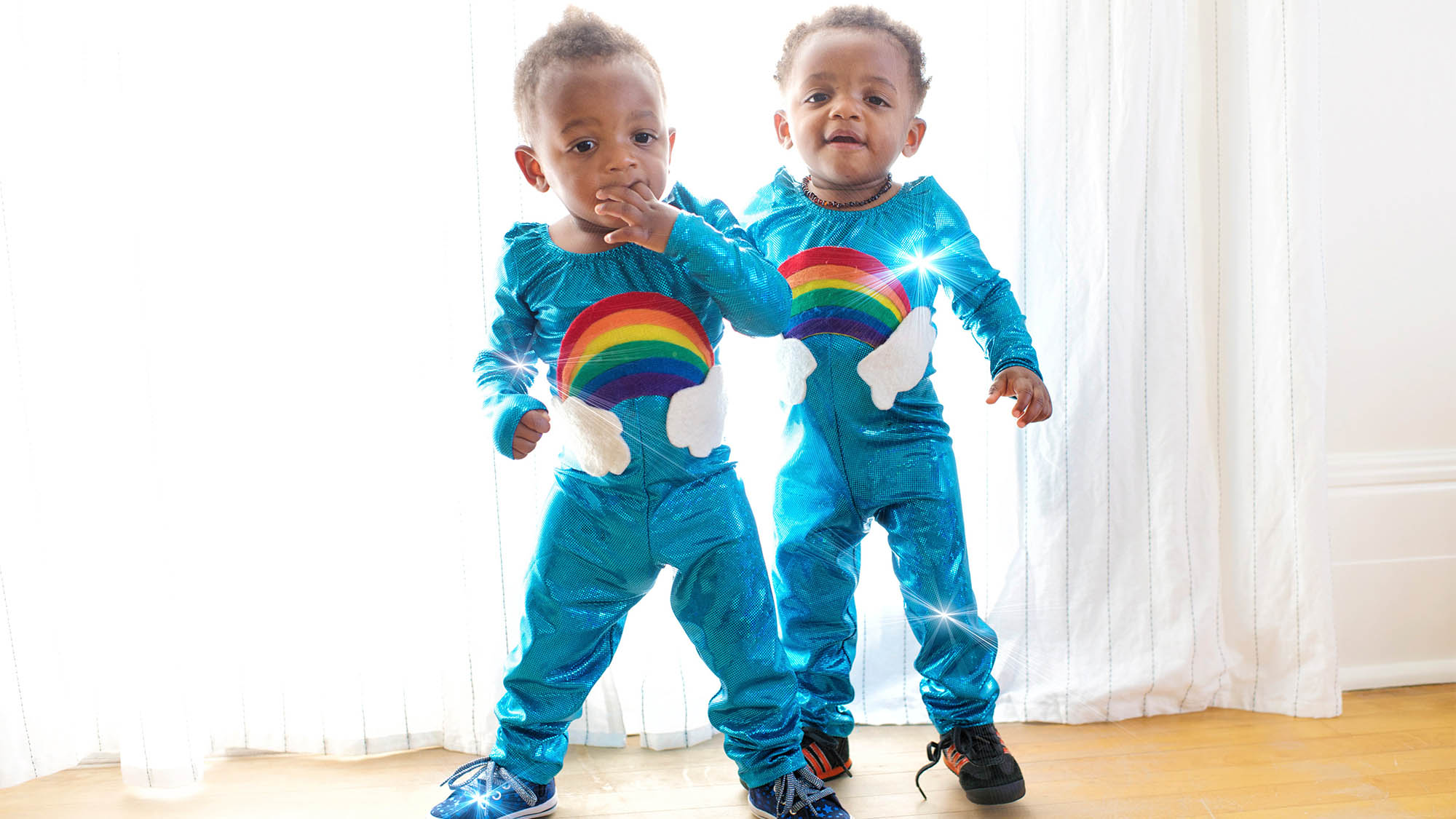 Two Toddler Boys Dressed in Matching Blue Jumpsuits with Rainbows