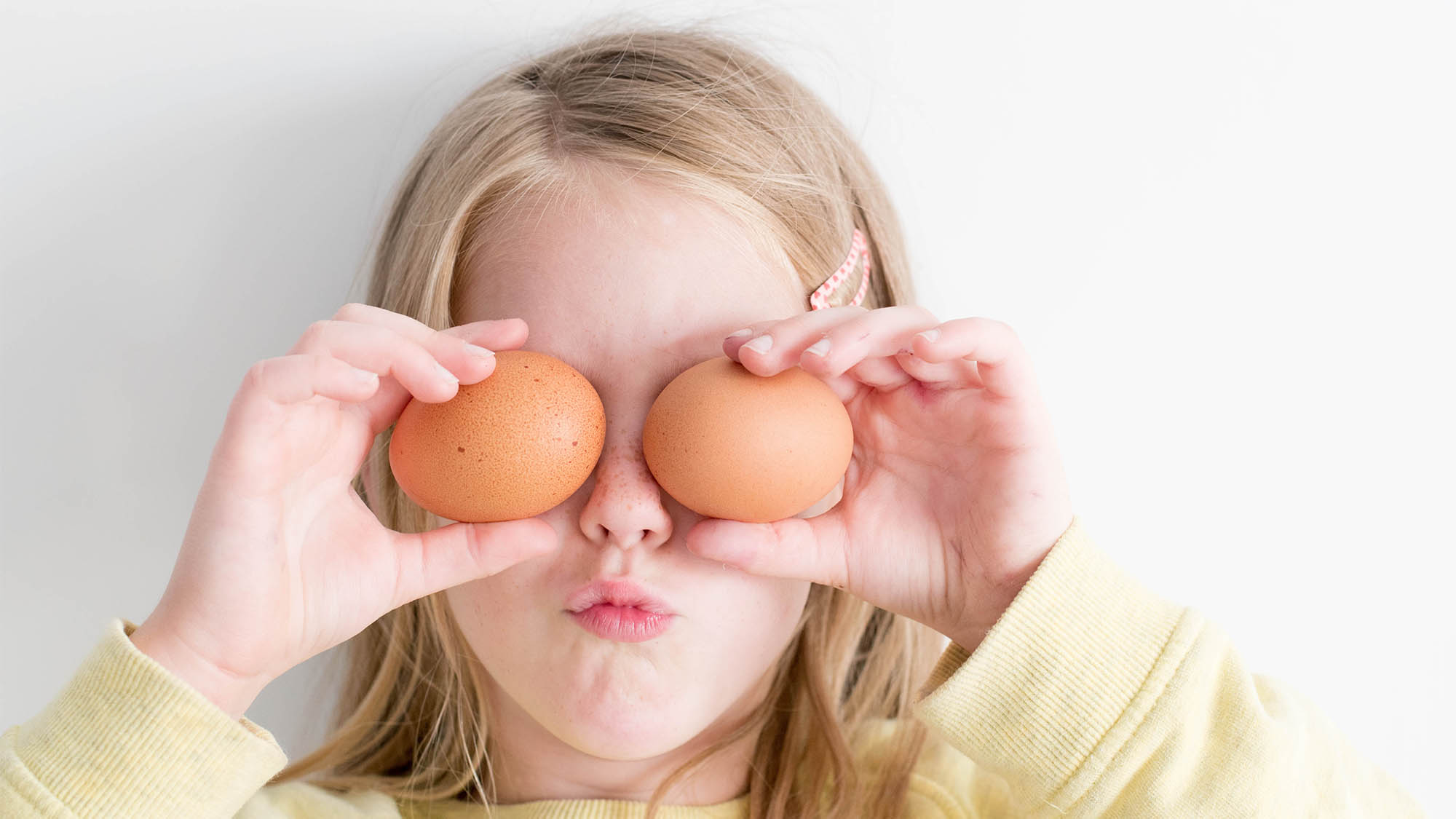 Little Girl Holding Two Eggs Over Her Eyes