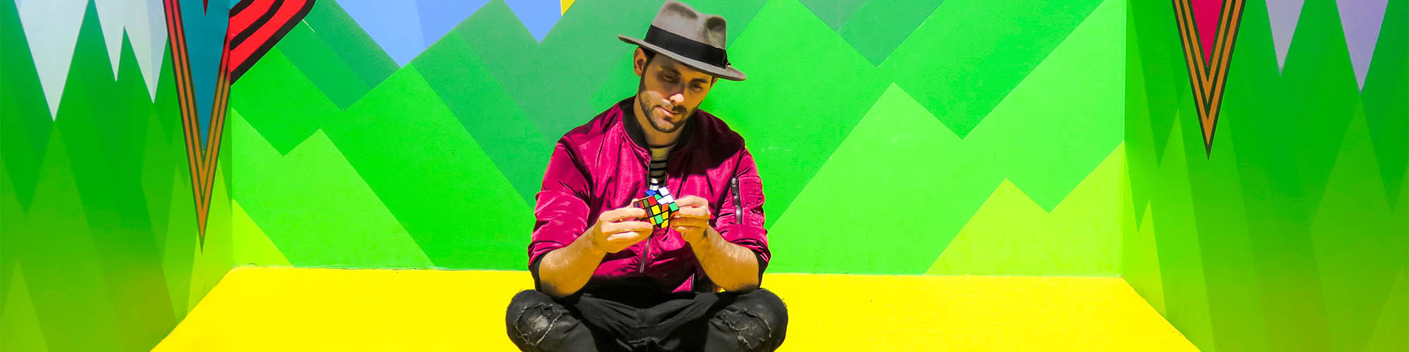 Man Sitting Doing Rubick's Cube with Newon Green Background