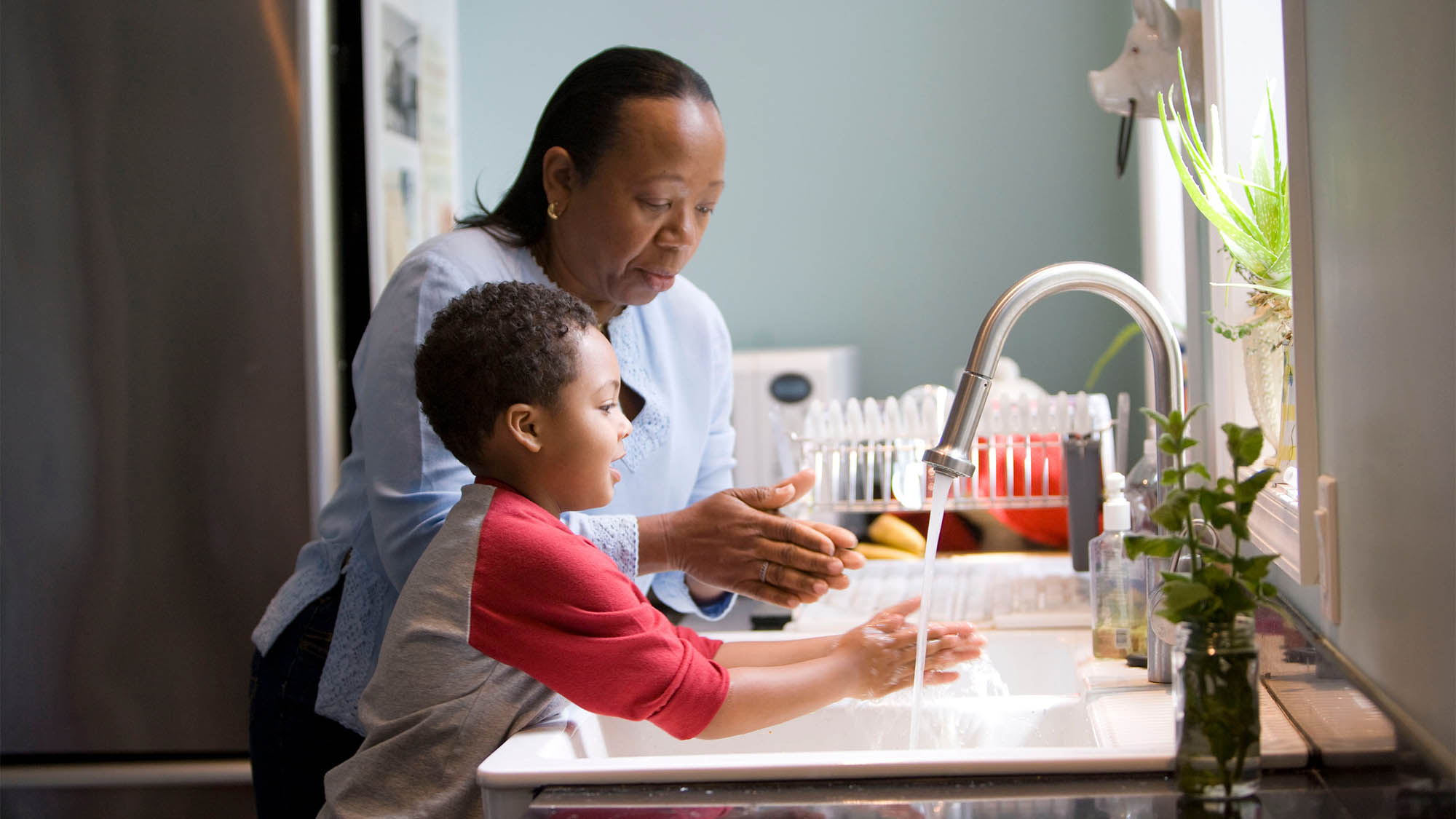 Mother and Son Washing Hands at Kitchen Sink