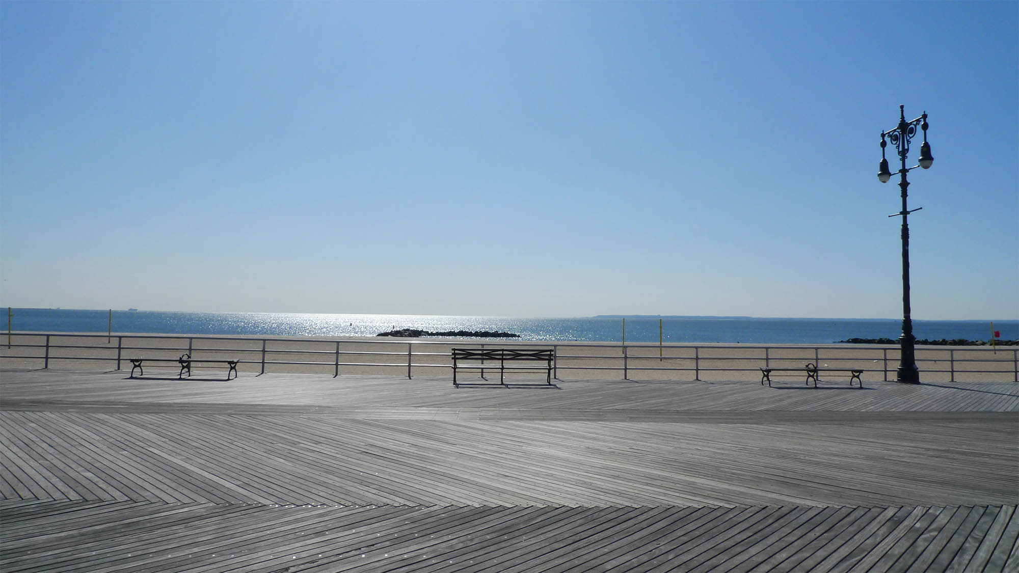 Vacant Coney Island Boardwalk with bench overlooking ocean