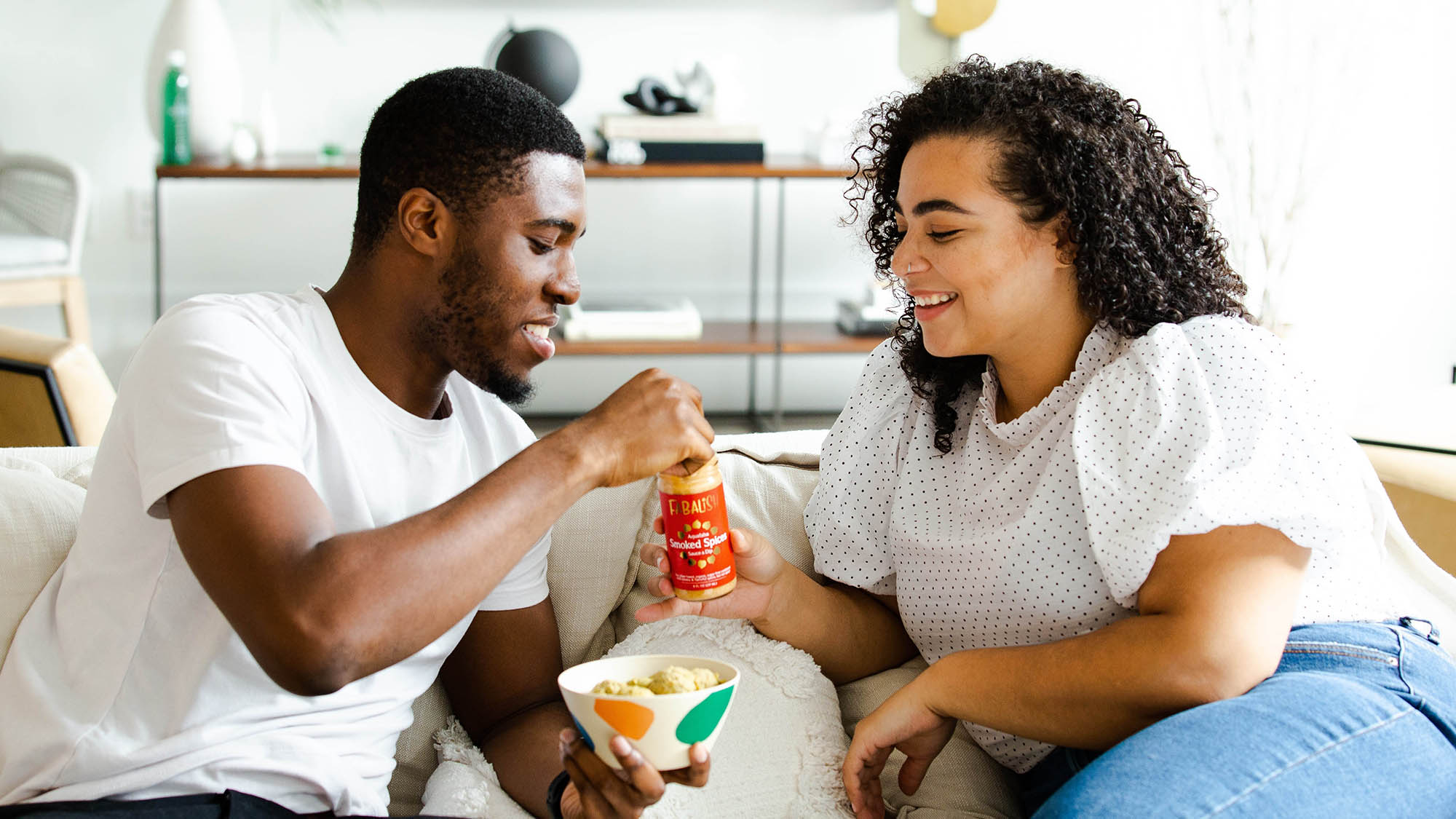 Couple on Living Room Couch Eating Snacks Smiling