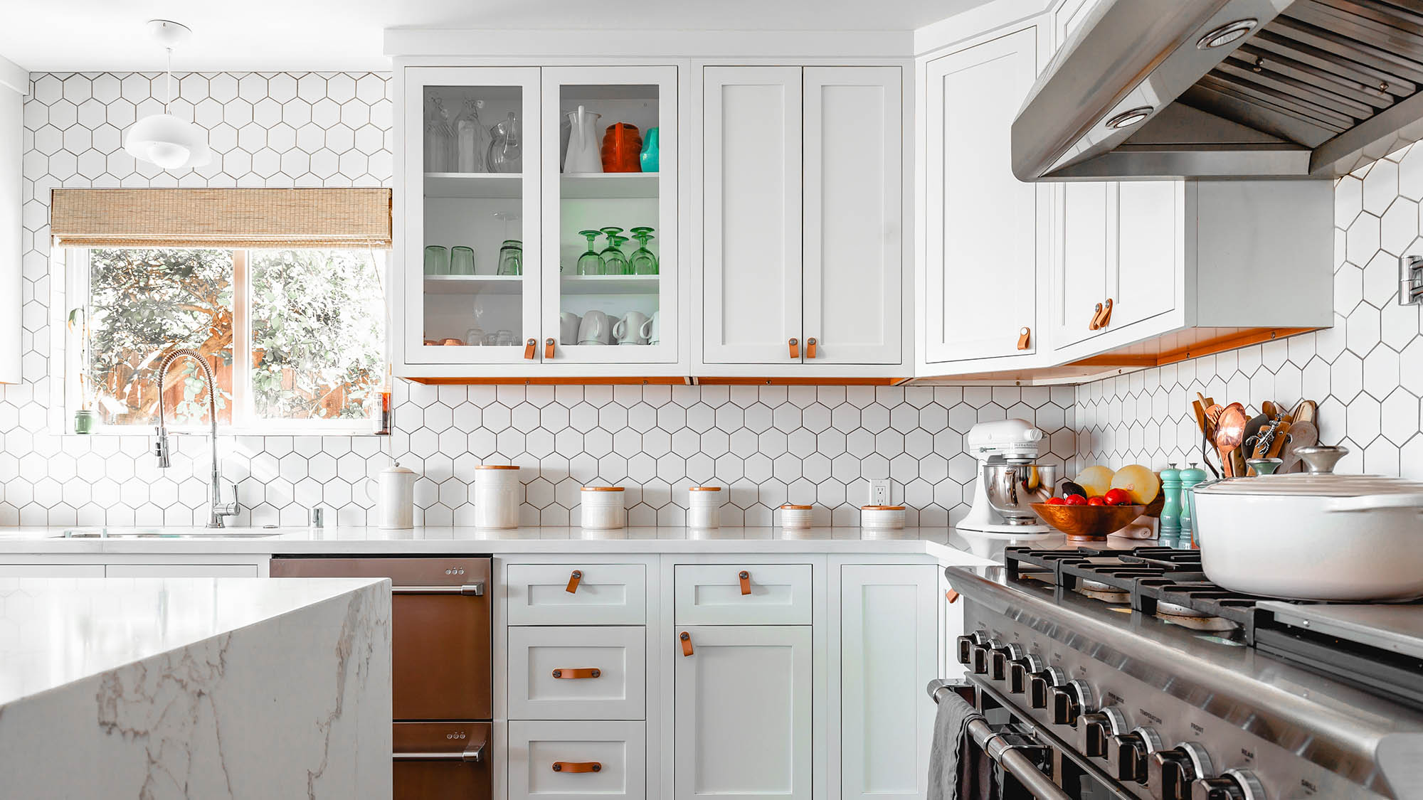 White tiled kitchen with white cabinets and leather pulls