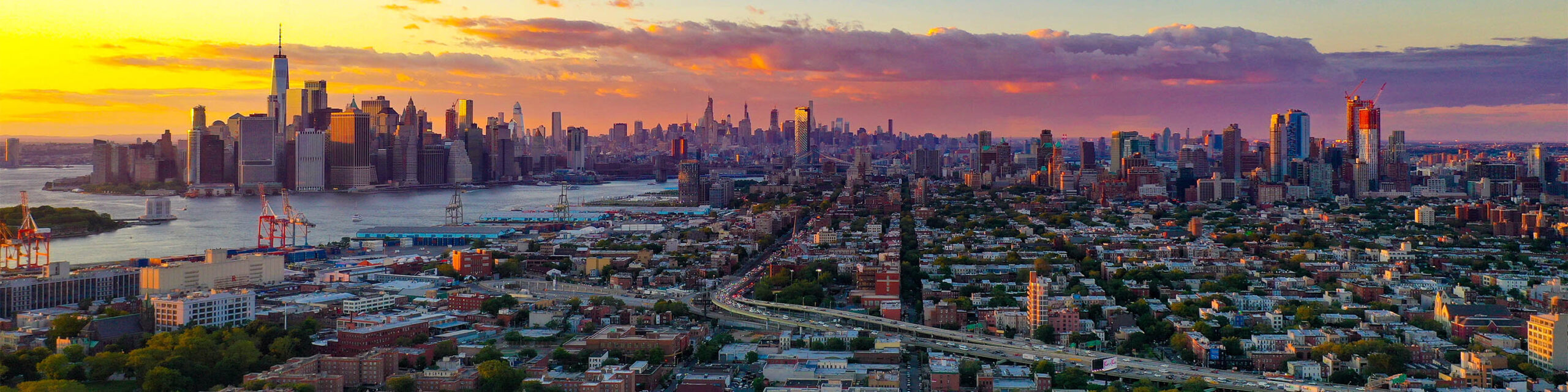 Manhattan skyline and aerial Brooklyn view from Brooklyn at sunset with pink and purple sky