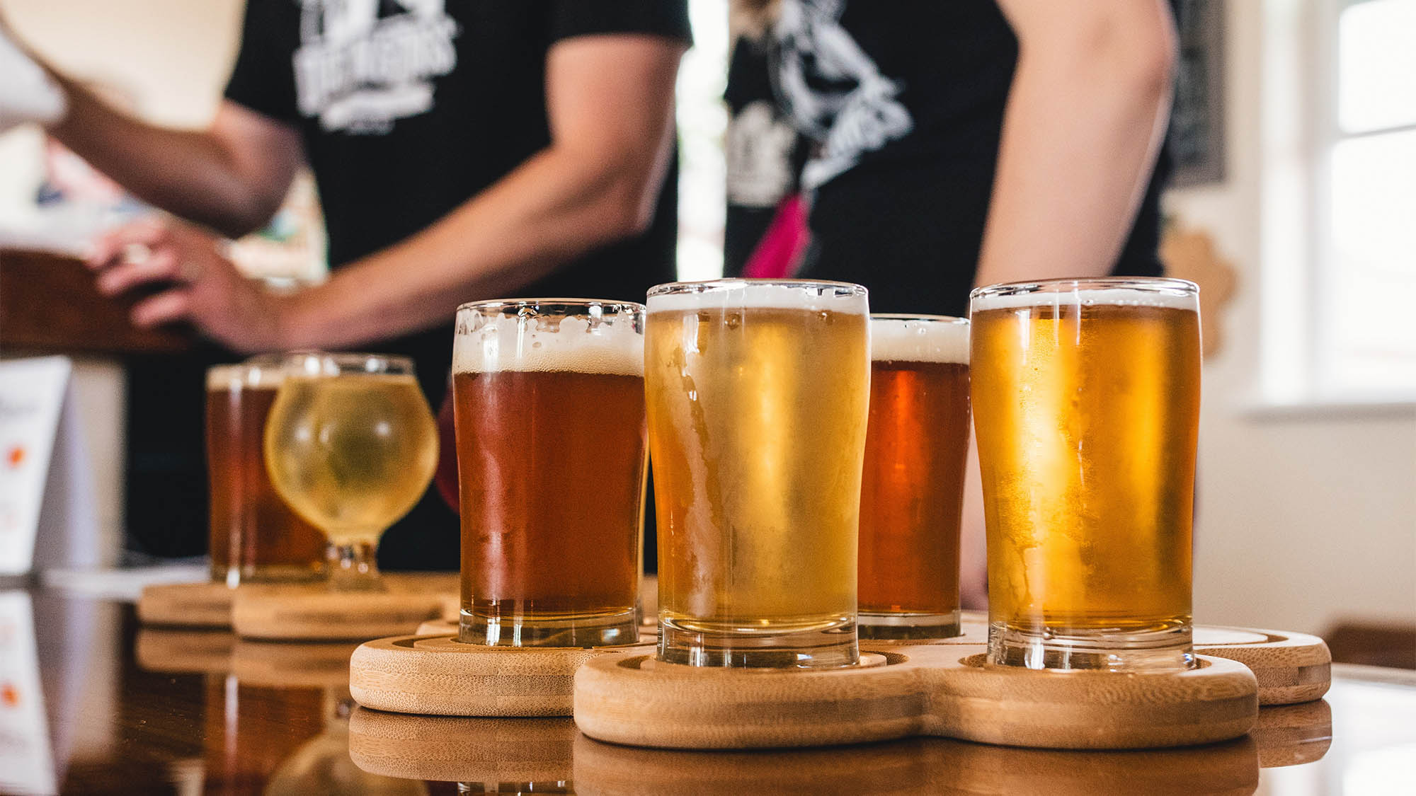 Flight of beers in different glasses on wood coasters
