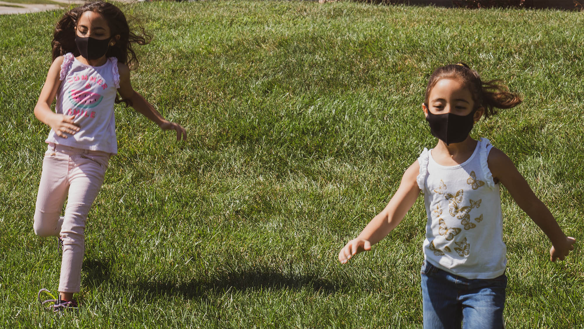 Two masked girls running in grass