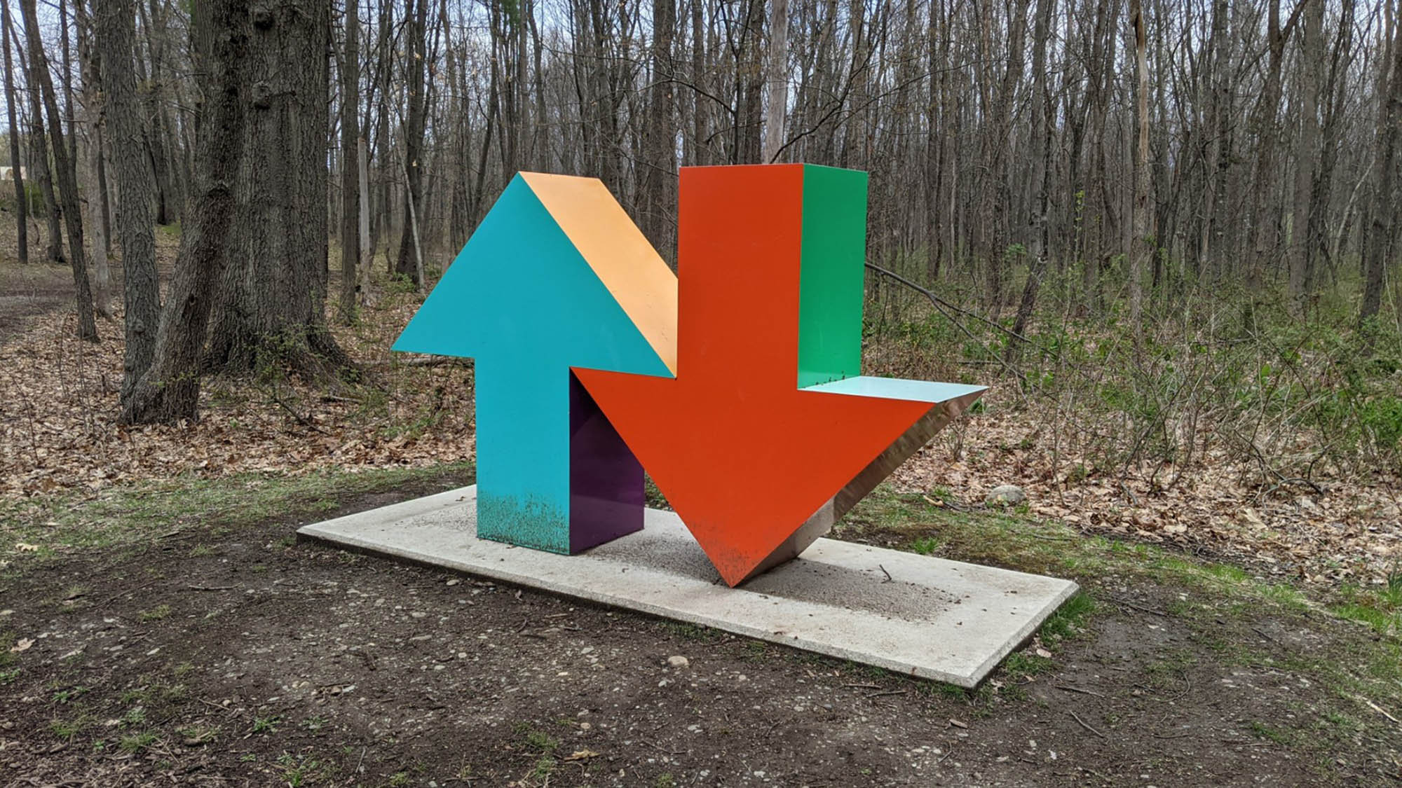 Large outdoor sculpture of blue arrow pointing up and red arrow pointing down at sculpture park