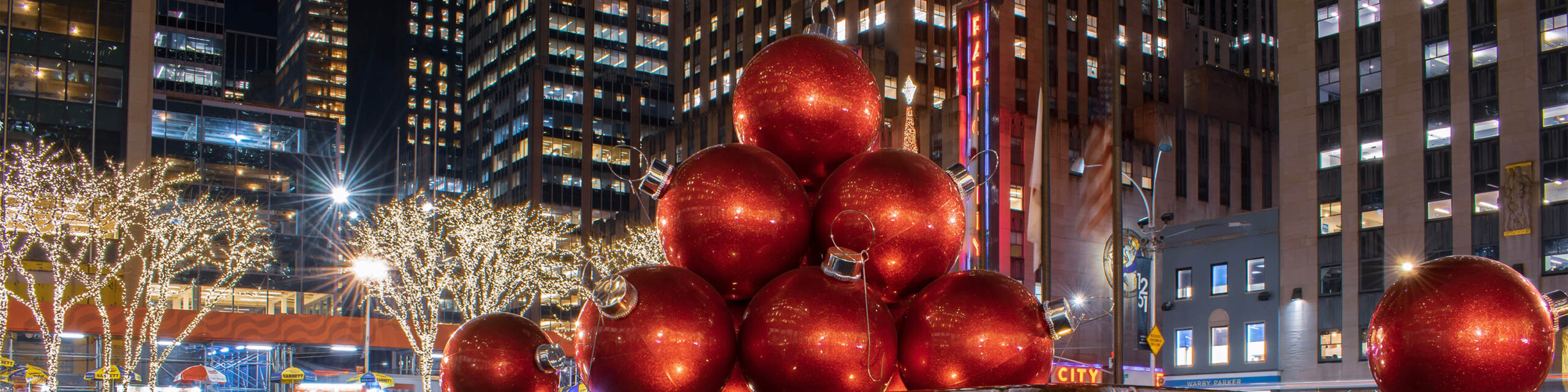 GIant red ball holiday ornaments and Radio City Music in background on NYC street