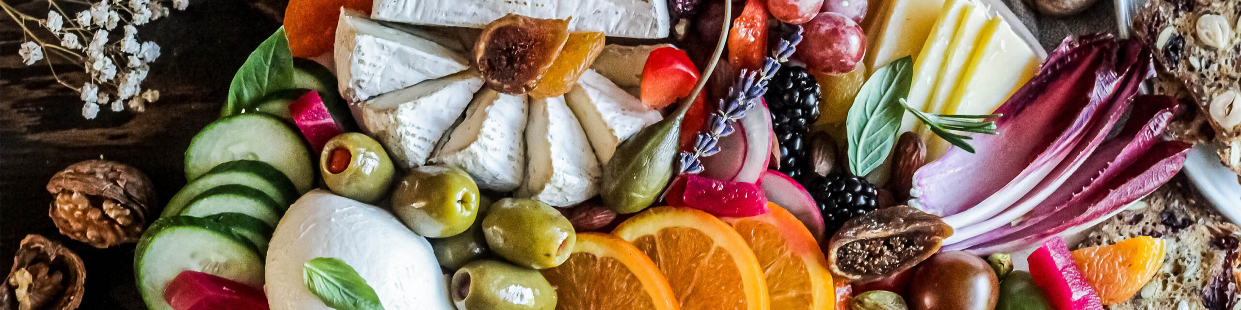 Charcuterie board with cheeses oranges lettuces vegetables