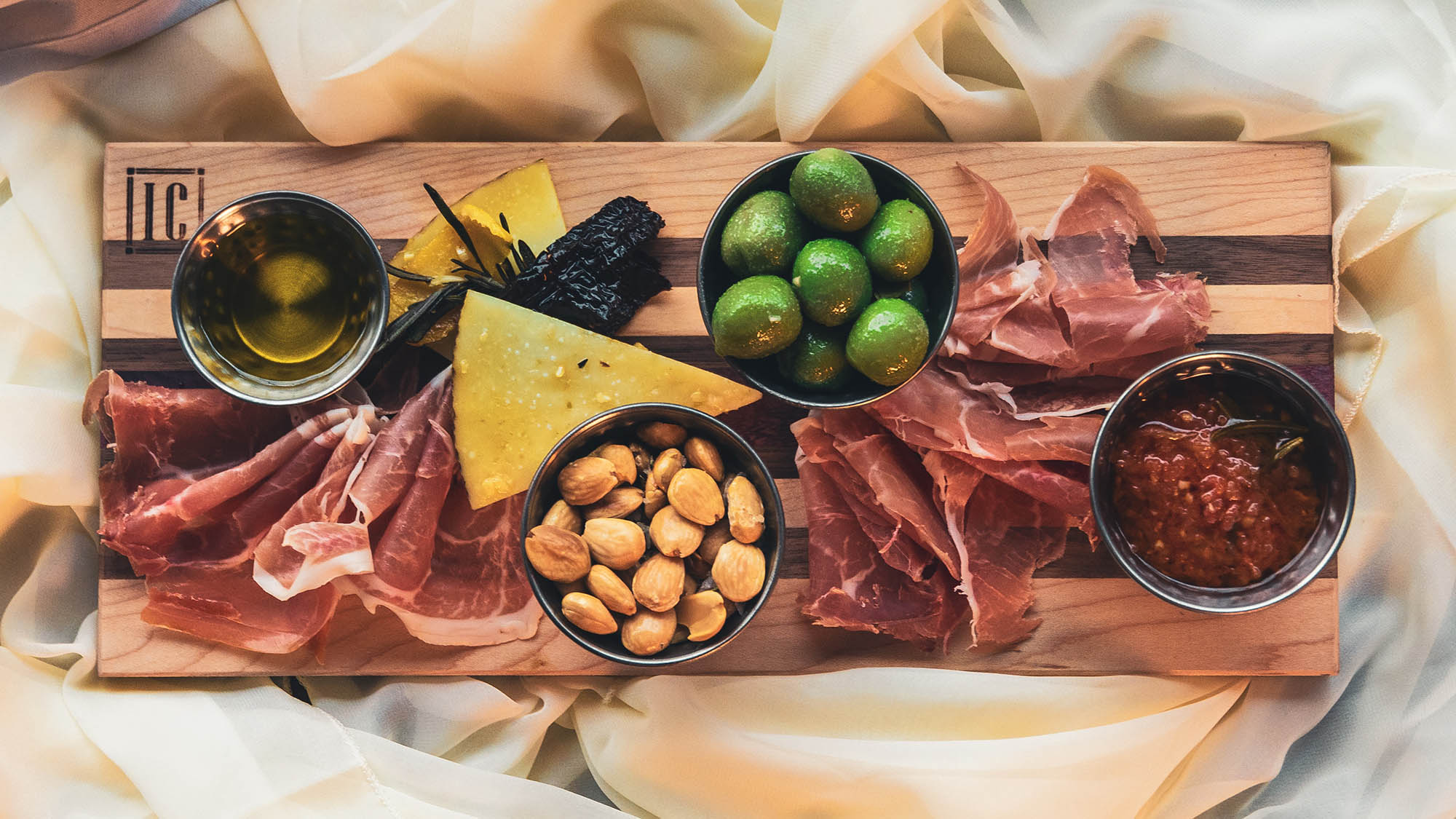 Charcuterie board with meats cheeses olives nuts and dip
