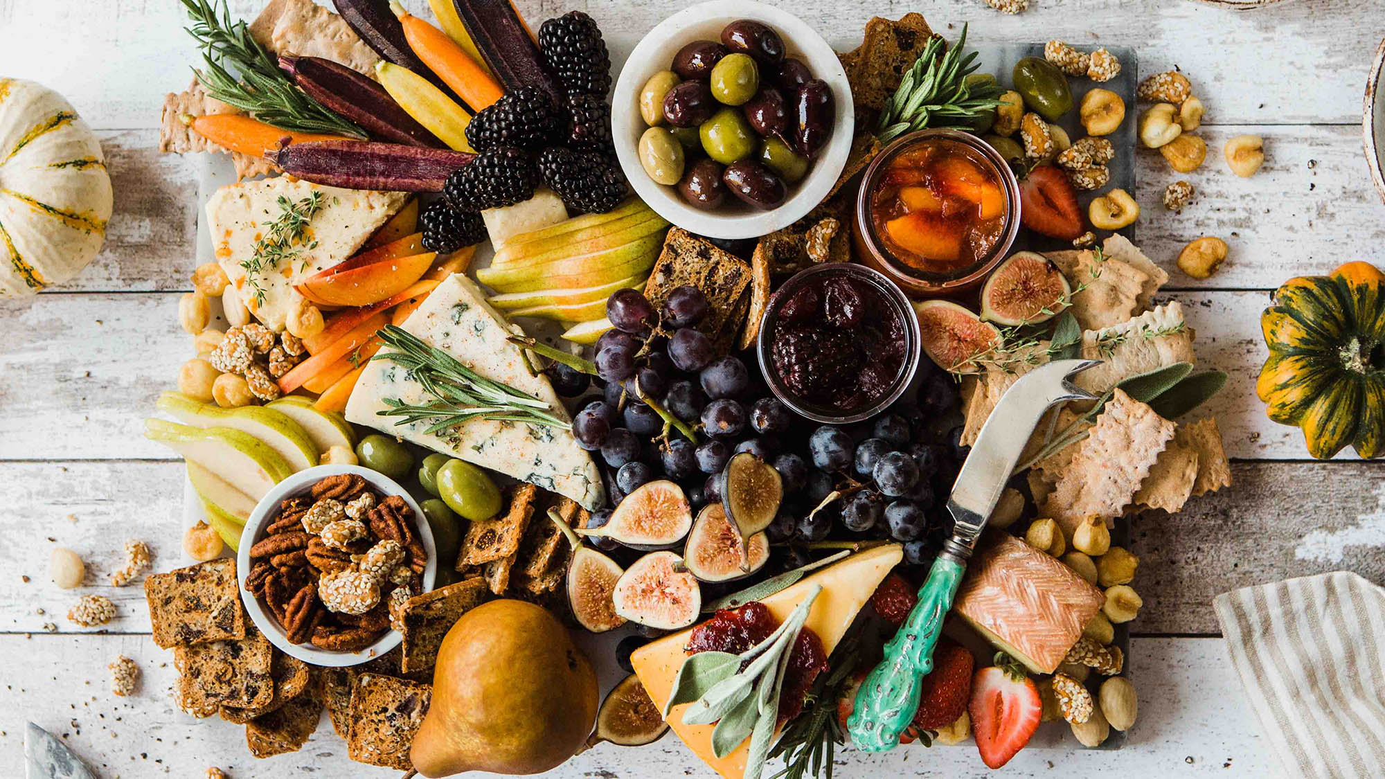 Charcuterie board with figs cheese nuts olives apricots herbs and veggies