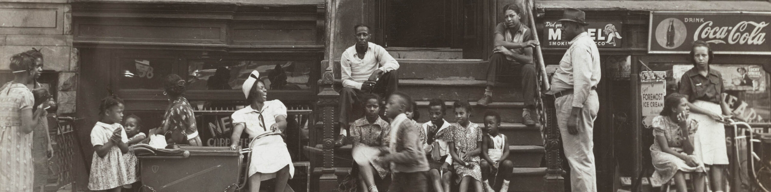 Black and white historical photo of African Americans sitting on stoop