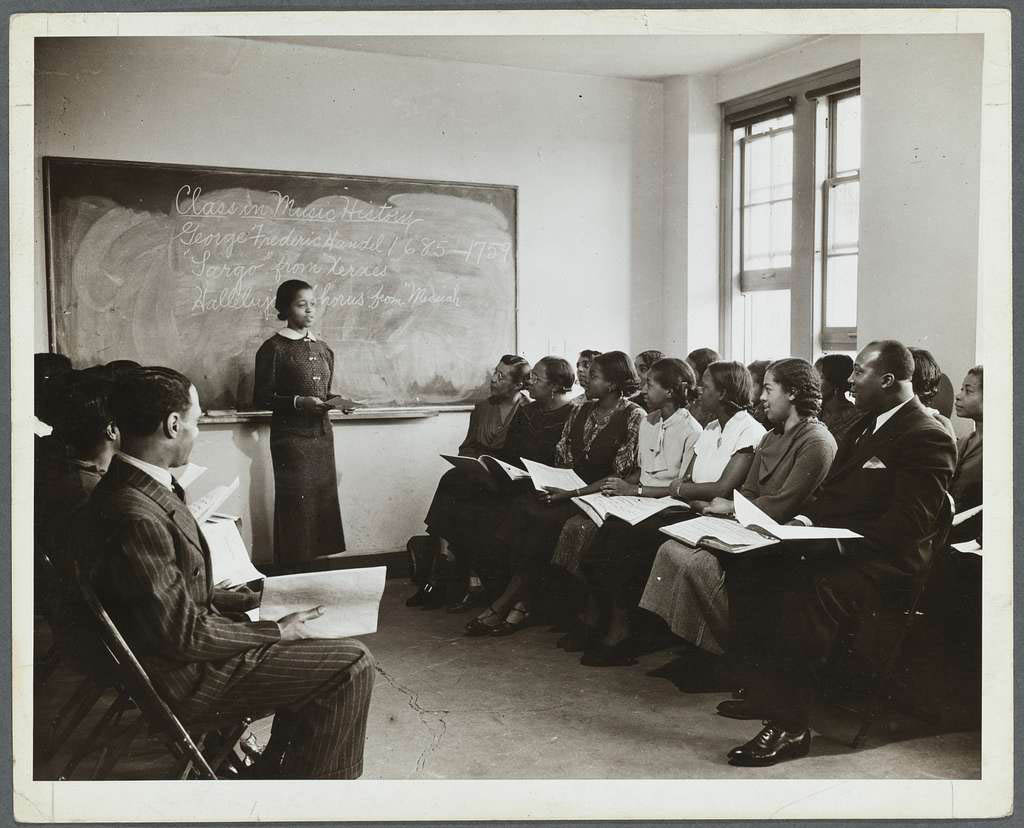 Black and white historical photo of Black woman teaching Black students in NYC