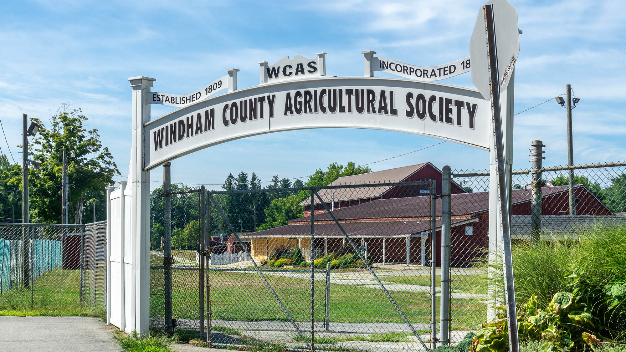 Windham County Agricultural Society sign with farmhouse and grass in background