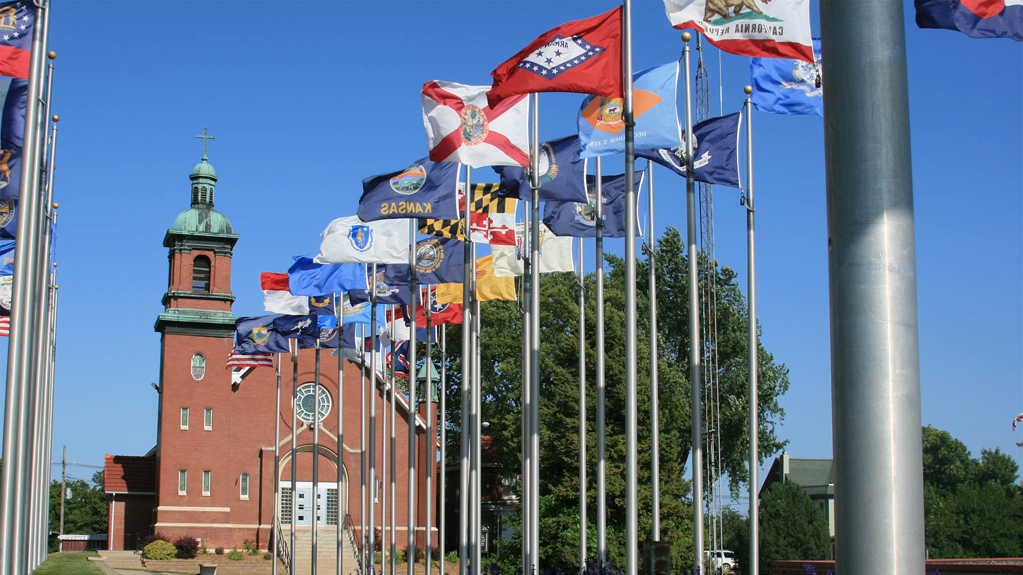 Diverse collection of flags on display in front of a brick church in Brooklyn Iowa