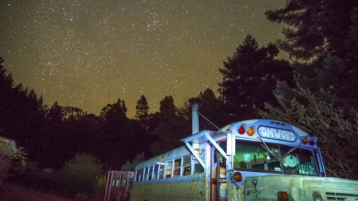 Boho-style schoolbus hotel at night under starry skies