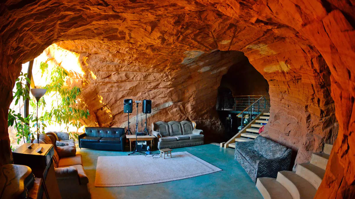 Interior living room of cave vacation home with black leather couch and cave wall in background