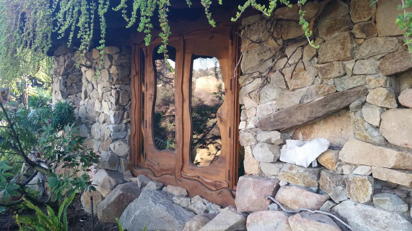 House exterior with rock wall and Hobbit-style whimsical wood and glass double doors