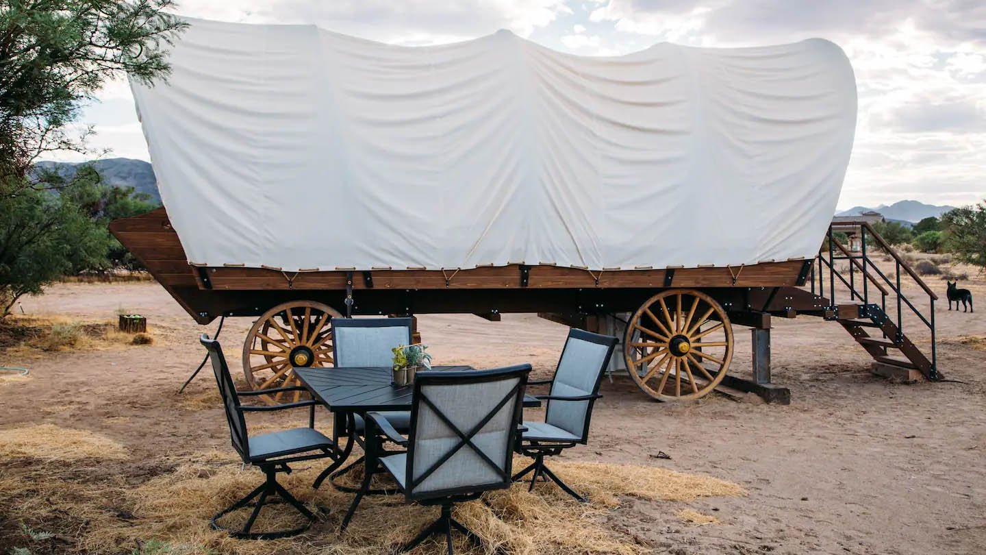 Exterior covered wagon hotel with four-seater table in front of it