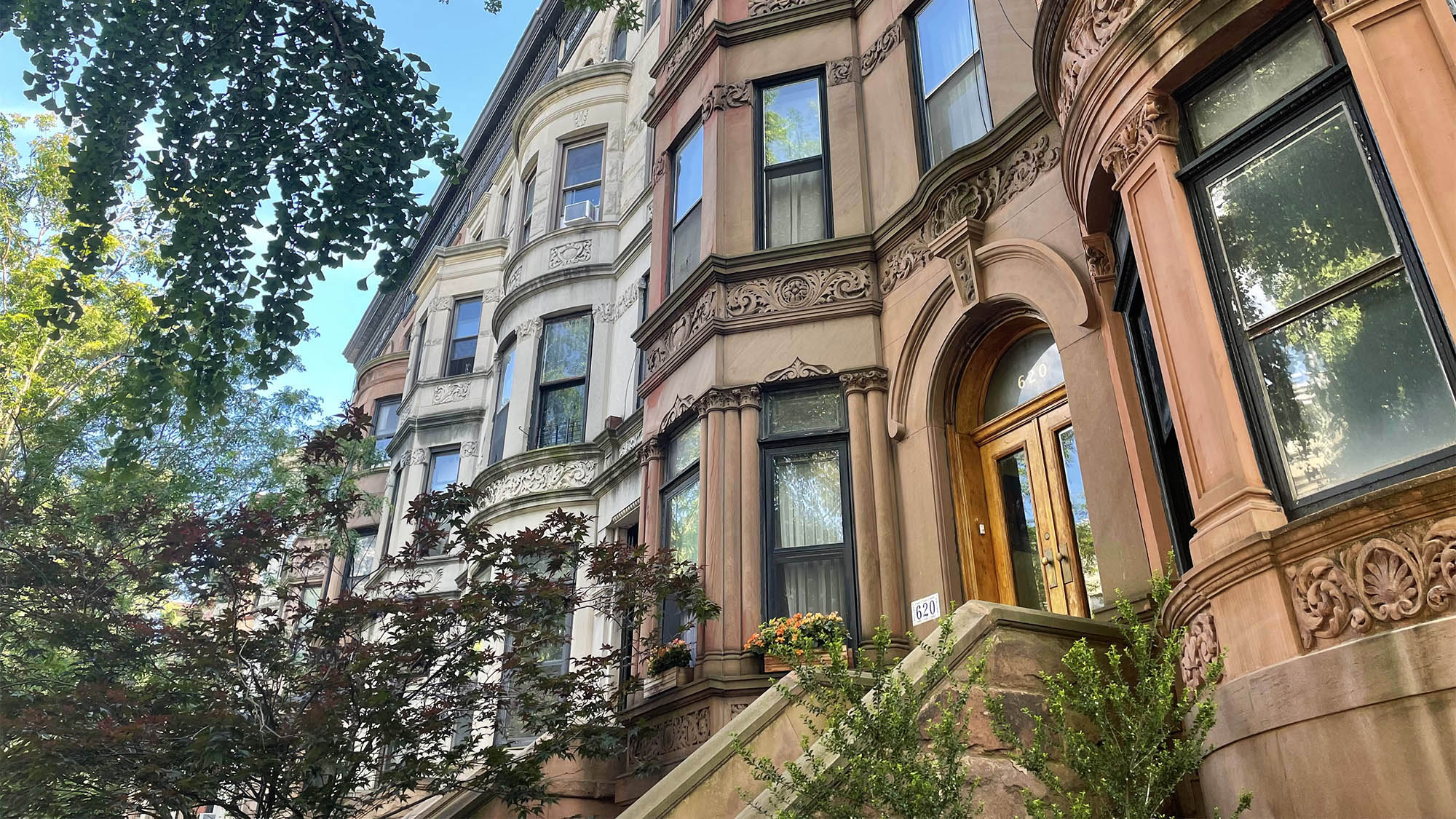 Row of Brooklyn brownstone buildings with trees and blue sky