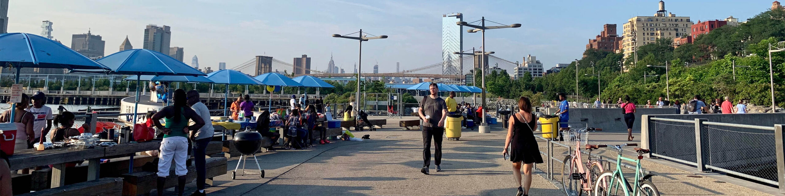 People walking along Brooklyn esplanade during outdoor festival with blue tents