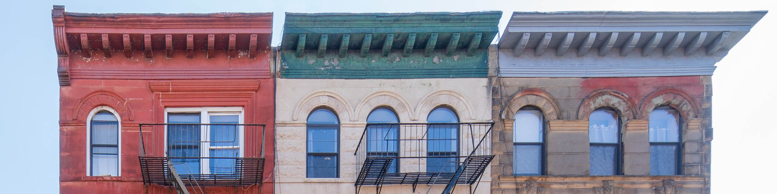 Top floor exterior of three Brooklyn buildings with fire escapes