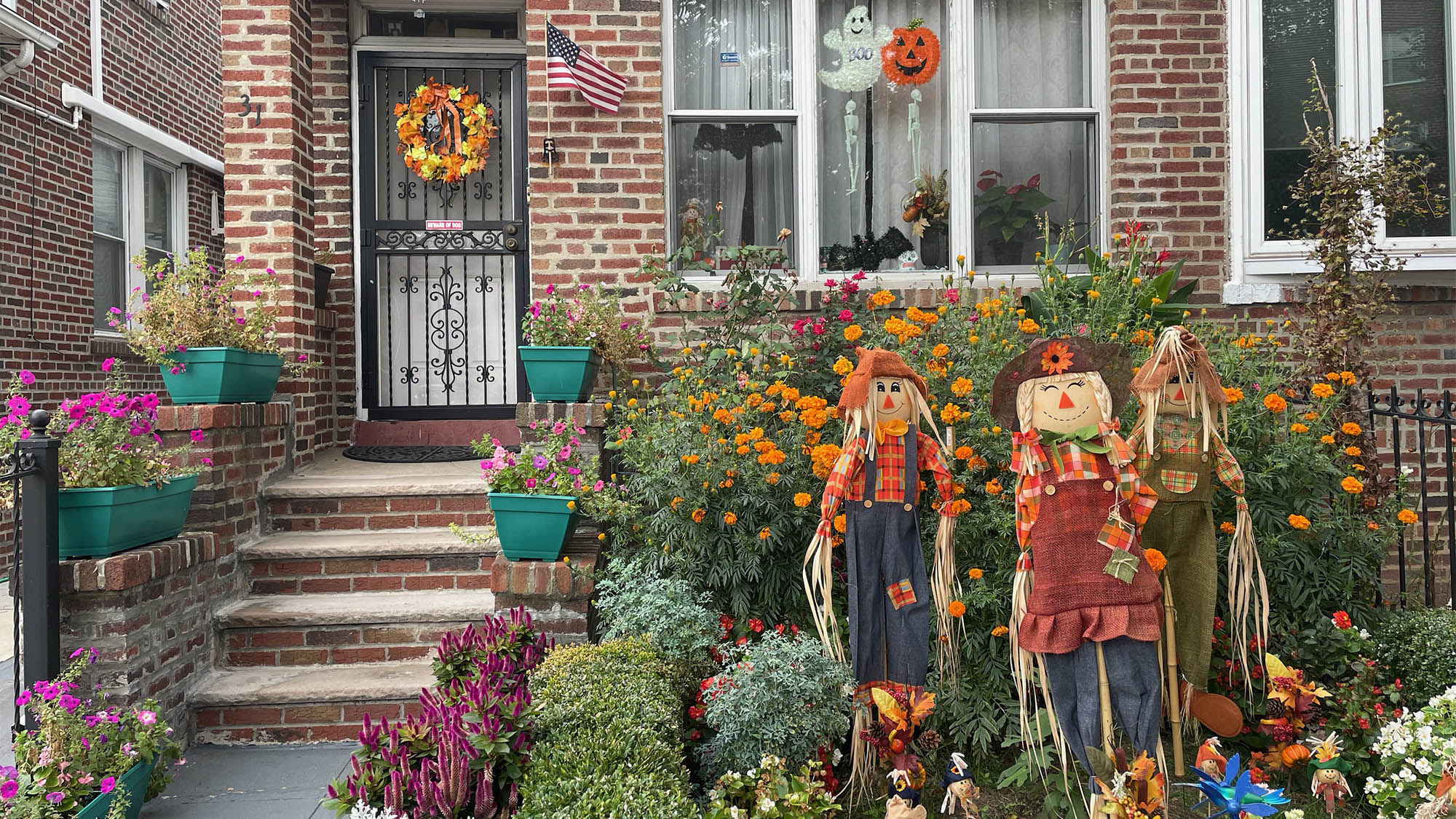 Scarecrows in front yard with brick house in background