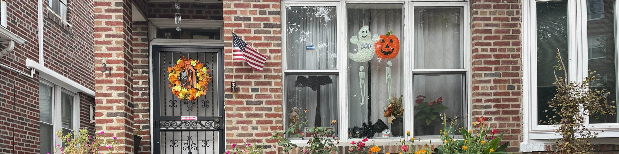 Front door with fall wreat and exterior windows with Halloween ghost and pumpkin decor