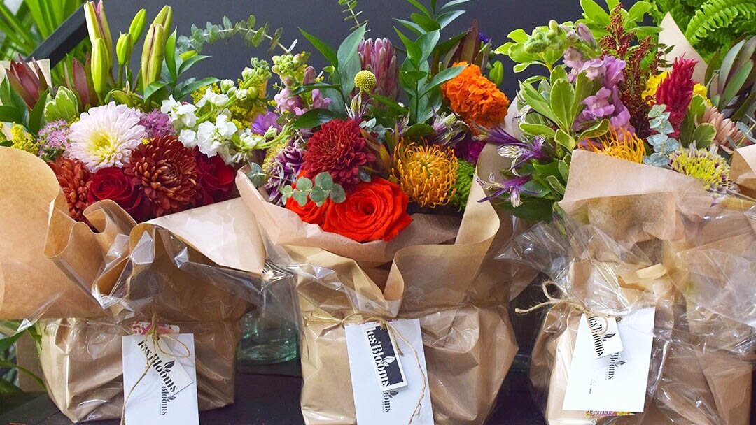 Three colorful flower bouquets in brown paper