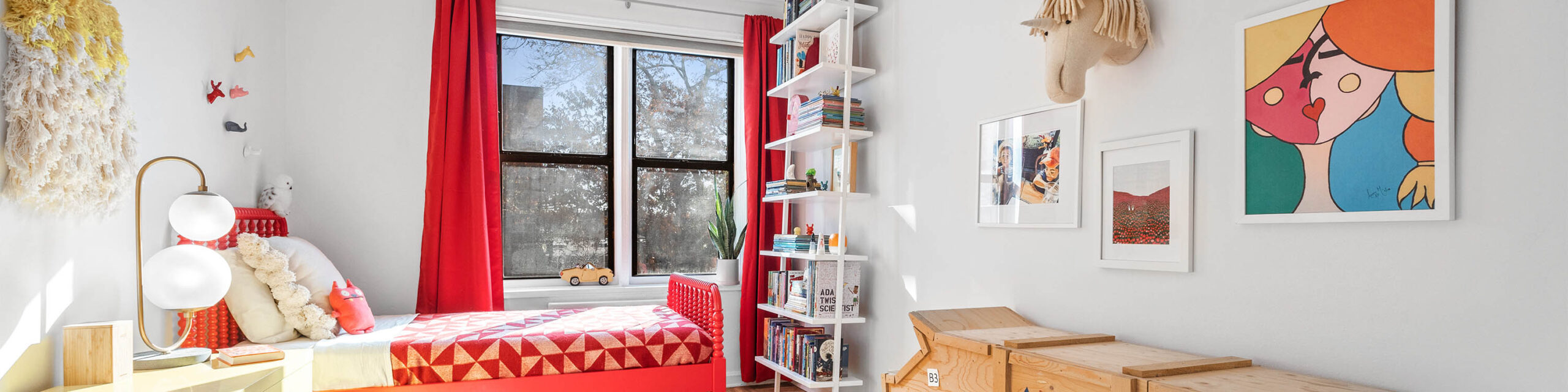 Bright kids bedroom with bed on left, two center wall windows and art on right wall