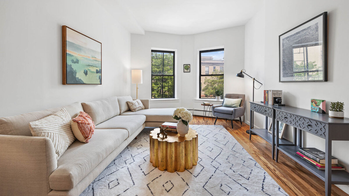 Living room with left side couch, area rug, coffee table and two windows on rear wall