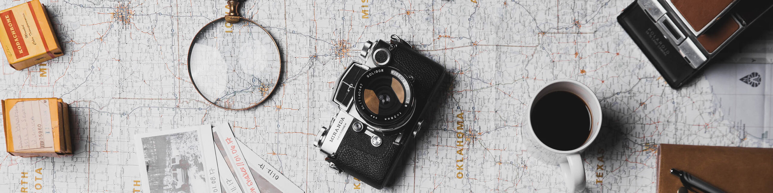 Camera film, magnifying glass, camera, coffee mug and other camera laid out on table