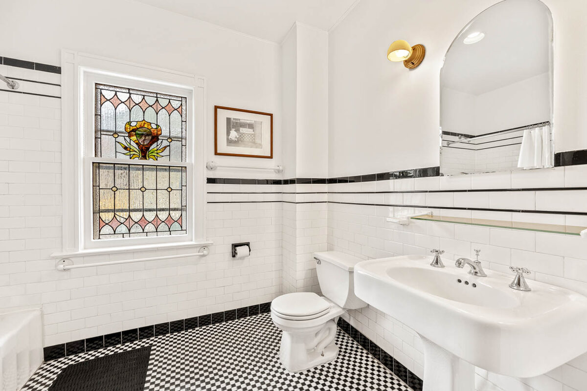 Vintage white bathroom with stained glass window and black and white tile floor