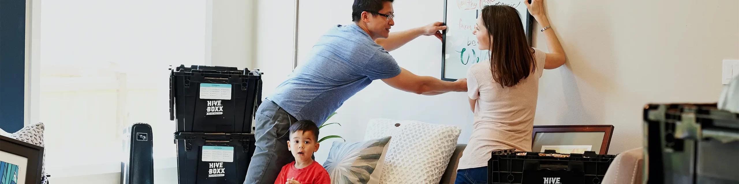 Man and woman hanging photo while toddler looks on