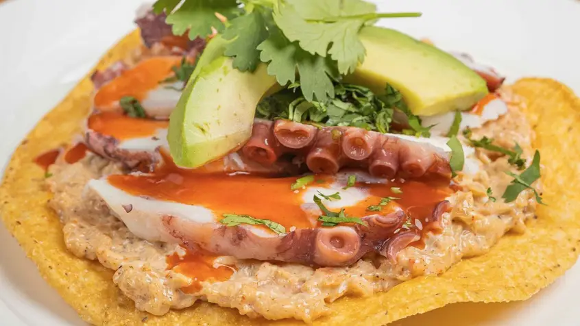 Octopus tostada with avocado and hot sauce 