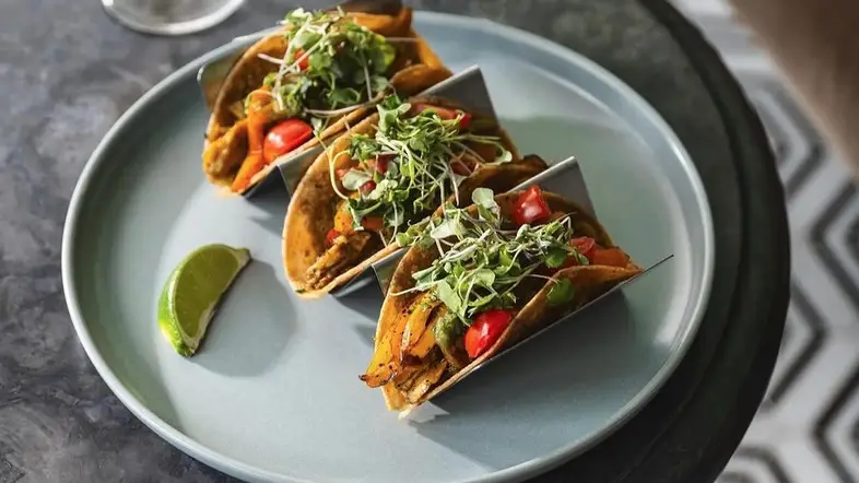 Three vegetarian tacos served with lime slice