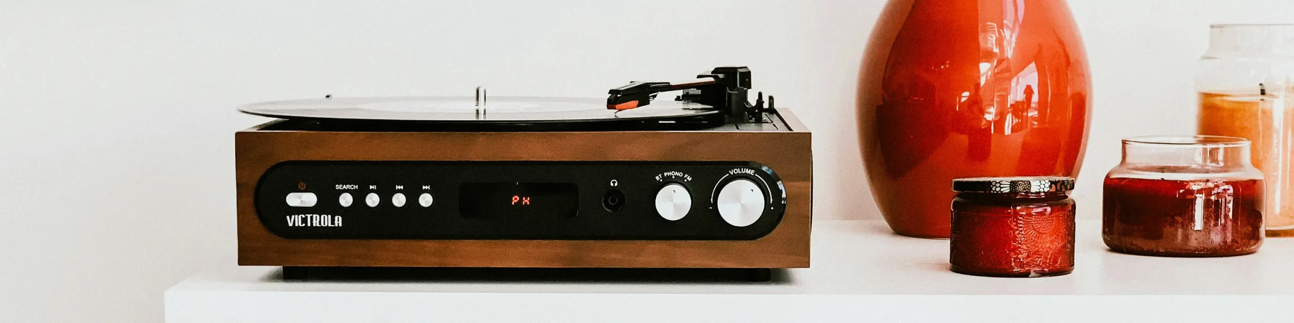 Record player on shelf next to vase and candle jars