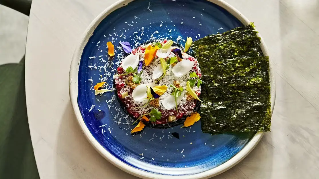 Tuna tartare topped with edible flowers and served aside nori sheet