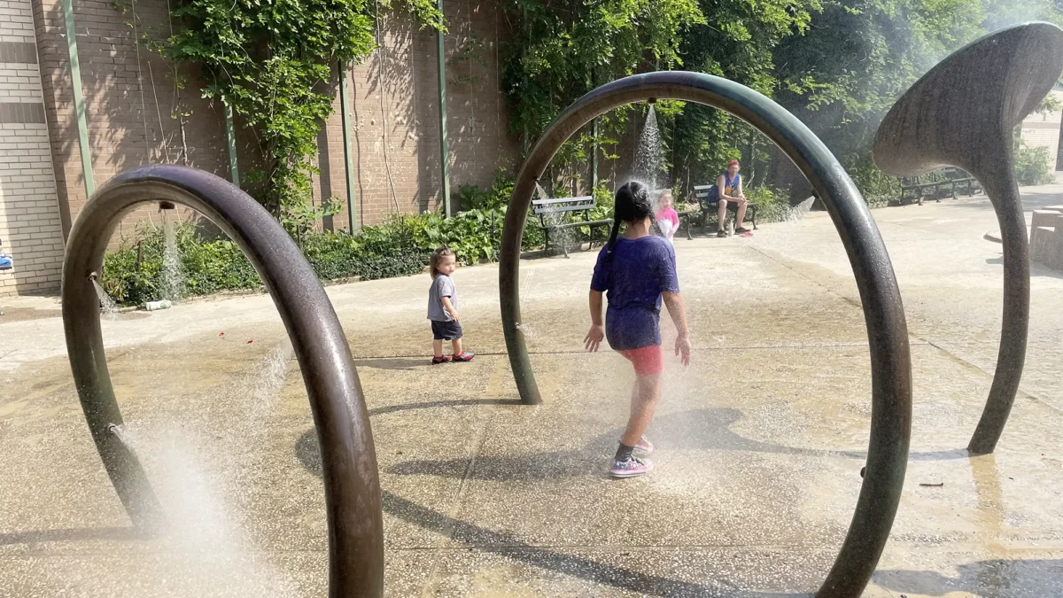 Girl walking through sprinkler at playground