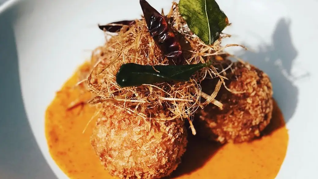 Three crab croquettes topped with chili peppers