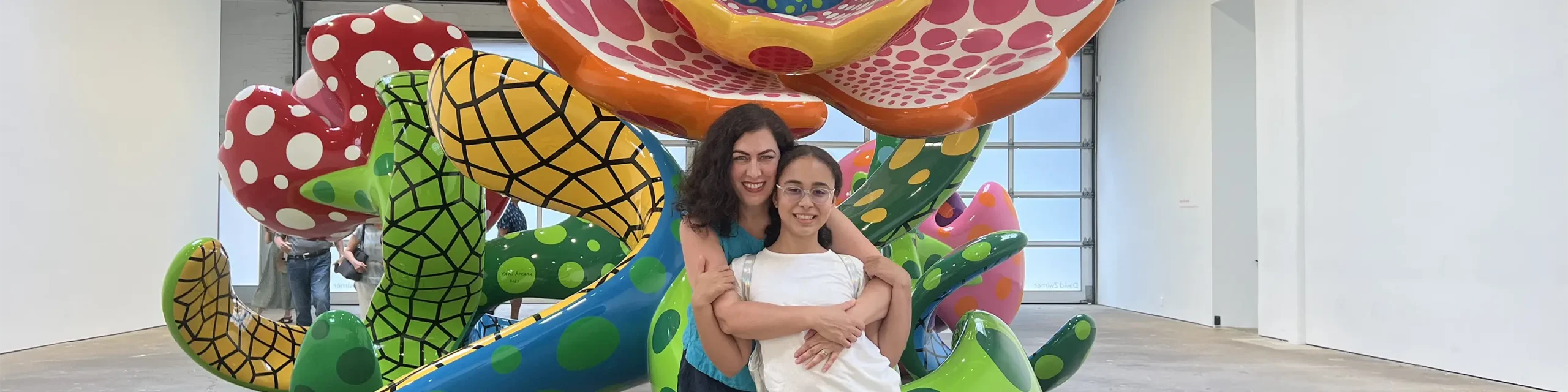 Mother hugging daughter in front of large floral sculpture