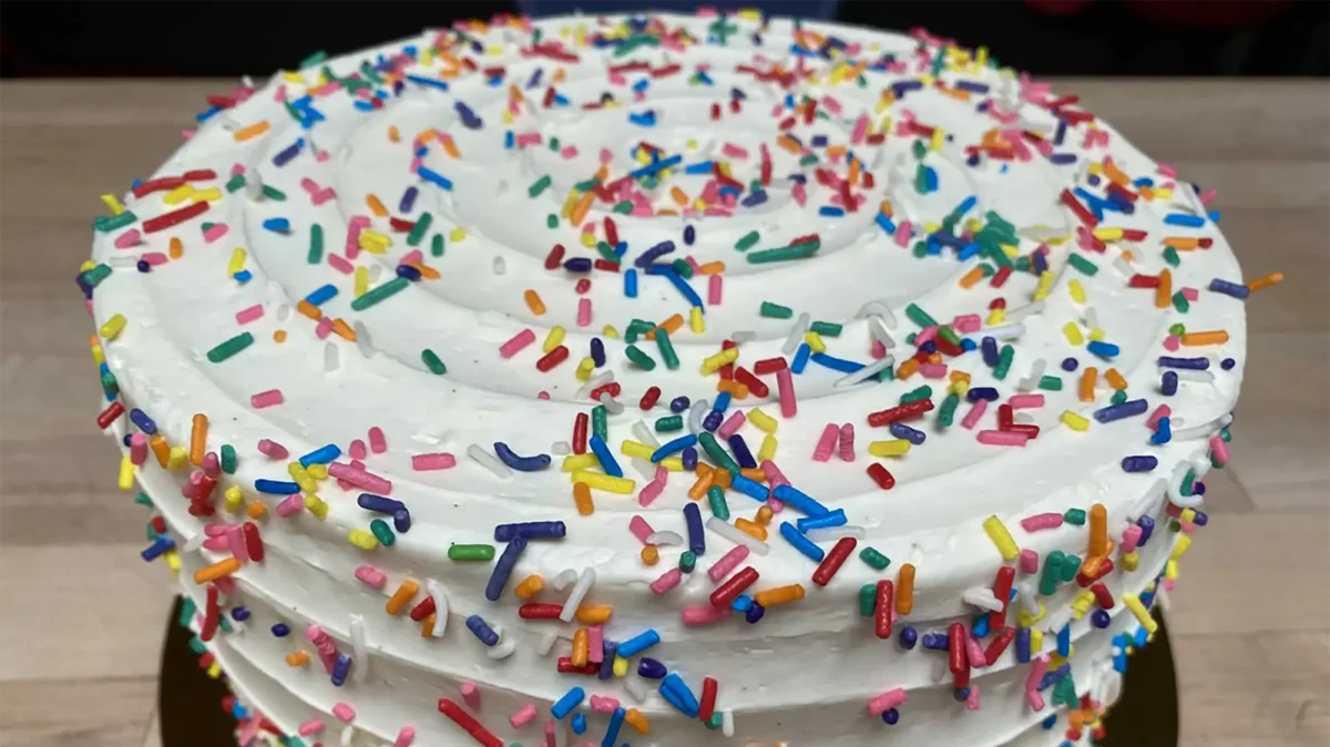 Cake with vanilla frosting and rainbow sprinkles