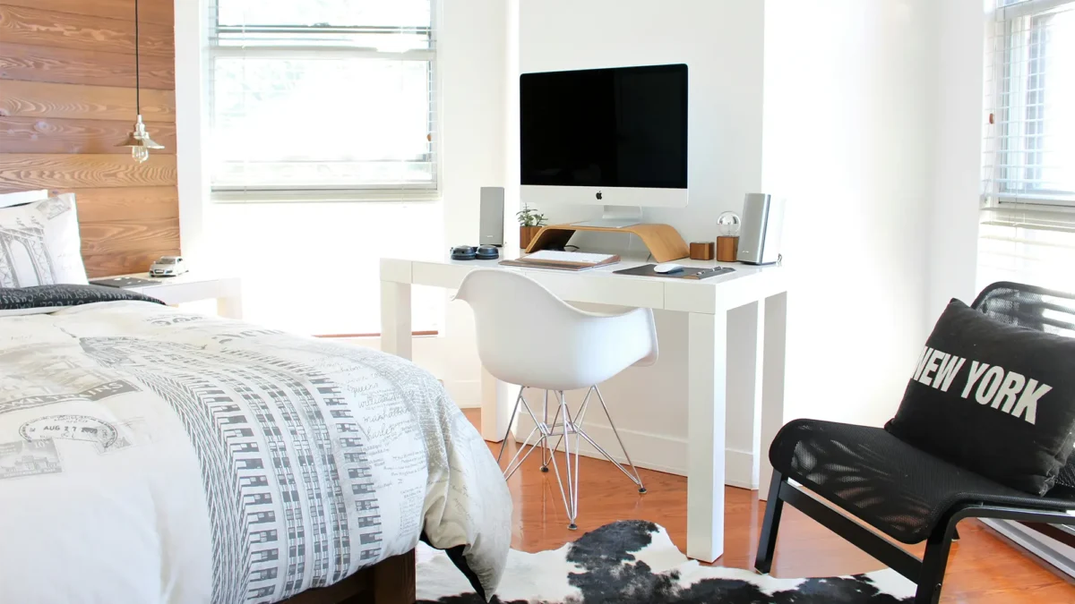 Bedroom with white computer desk and black chair with "New York" pillow