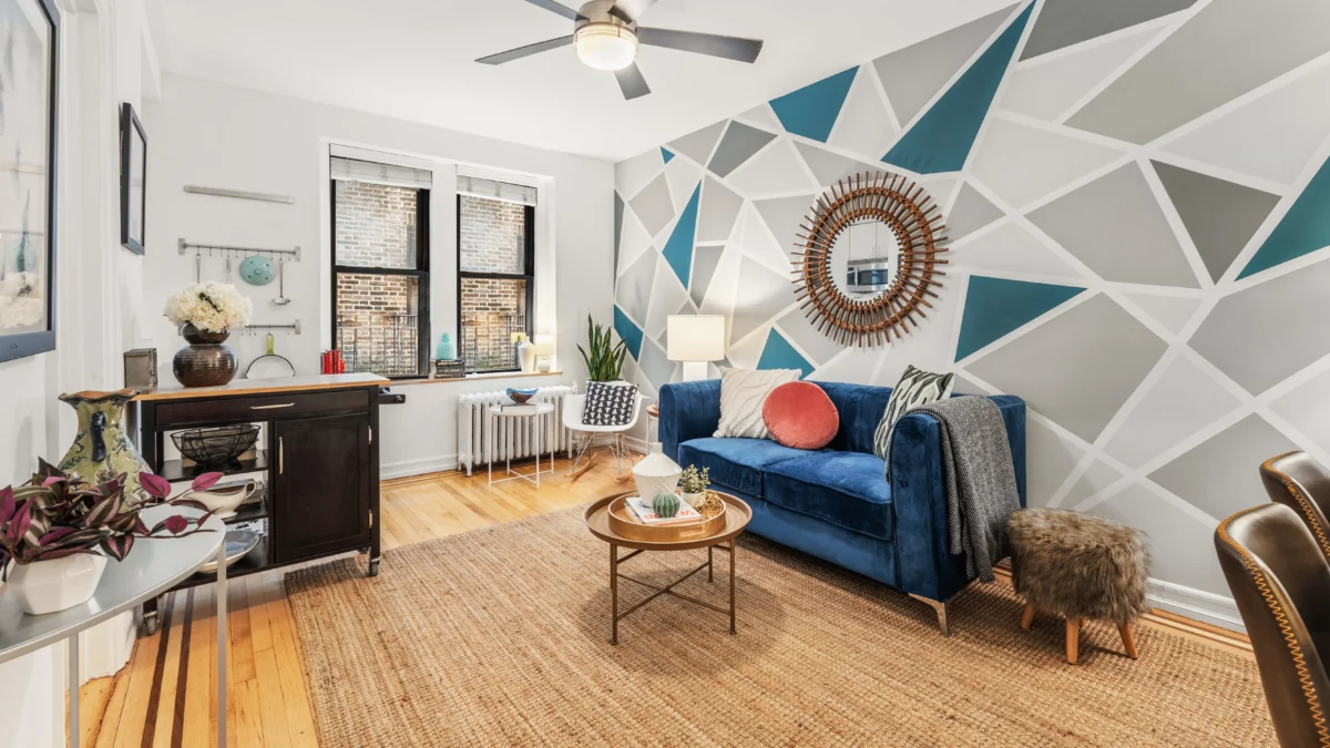 Apartment studio with blue couch along geometric pattern wallpaper and coffee table