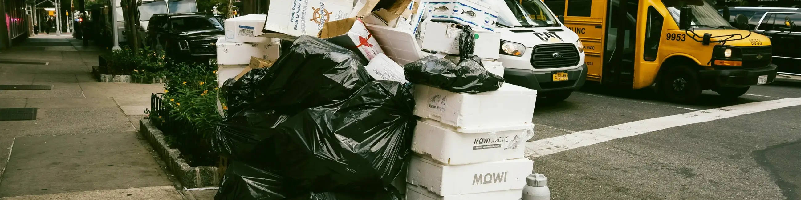rash heap on NYC street with school bus in background