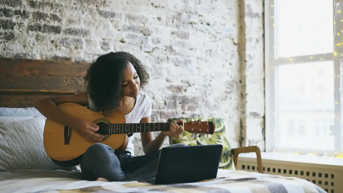 Girl playing guitar on bed