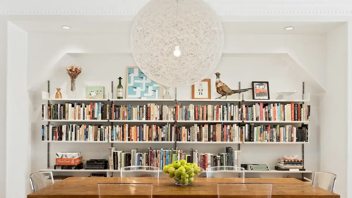 Crowded bookshelf wall behind dining table
