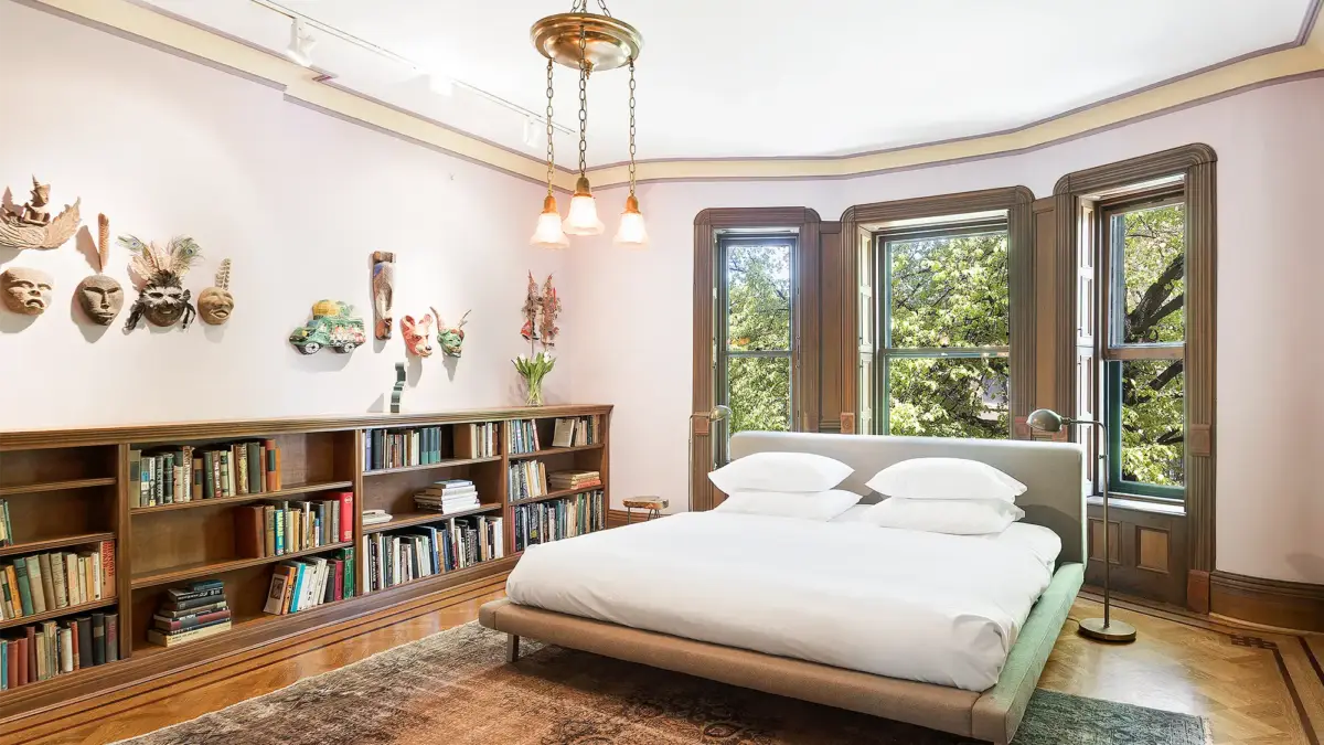 Low bookshelf with masks hanging above it and bed to the right