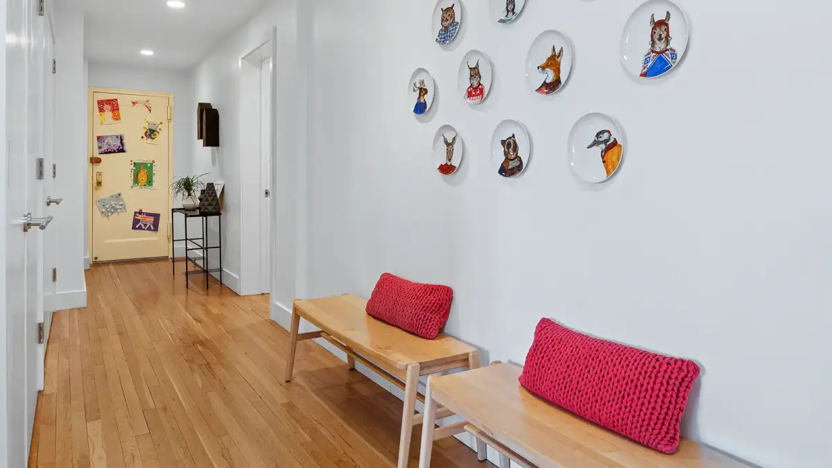 Entryway with two wooden benches and artistic plates on wall