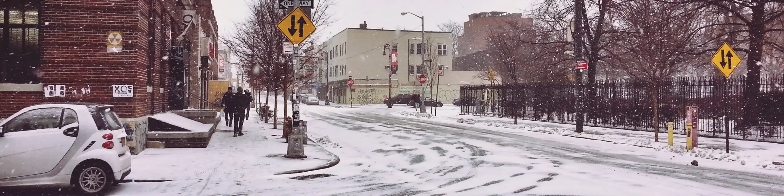 Greenpoint Brooklyn snowy street with two people walking on sidewalk